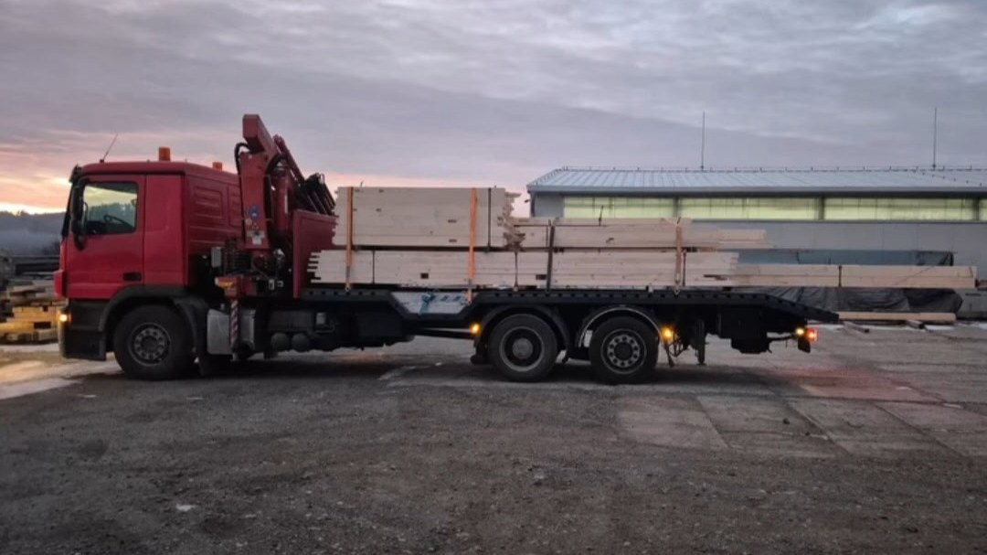 Nákladní auto s hydraulickou rukou převážející stavební materiál